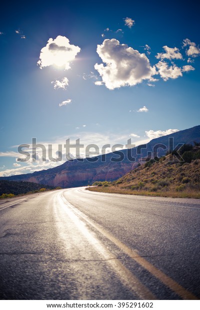 American landscape across long\
endless asphalt mountain road in beautiful sunny, Colorado,\
USA