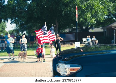 American lawn flags display front of modern pickup truck driving on residential street smalltown Fourth of July parade, Dallas, Texas, USA blurry crowd people waving hands. Independence Day patriot - Powered by Shutterstock