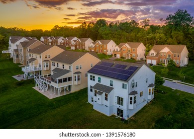 American Luxury Real Estate Single Family Houses With Brick Facade, Solar Power Roof  And Two Car Garages In A New Construction Maryland Street Neighborhood USA Aerial View During Sunset