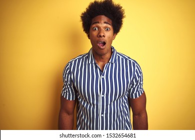 American man with afro hair wearing striped shirt standing over isolated yellow background afraid and shocked with surprise expression, fear and excited face. - Shutterstock ID 1532654681
