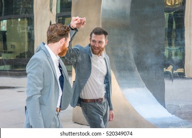 American Man with beard, mustache looking at mirror, wearing cadet blue suit, standing by metal mirror wall, looking at reflection. Concept of self assured, self esteem, self checking strategies.