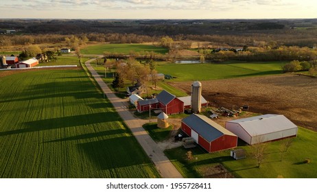 American midwestern countryside in springtime. Aerial view of farms with red barns in spring, rural road, agricultural fields