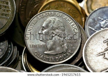 American one quarter coin with other countries different coins background, quarter dollar is a United States coin worth 25 cents with  the profile of George Washington on its obverse, selective focus.