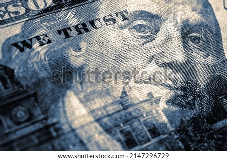 American paper money. 100 dollar bill with portrait of Benjamin Franklin in focus. US banknote closeup. Blue tinted illustration. Government debt and USA dollars. Bonds and treasuries. We trust