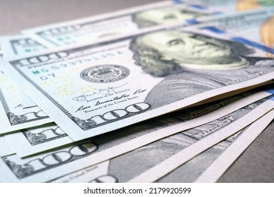 American Paper Money. Several One Hundred Dollar Notes Lie On A Gray Textured Surface. Focus On The Number 100. Savings Economy And The US Dollar. National Debt And Treasury