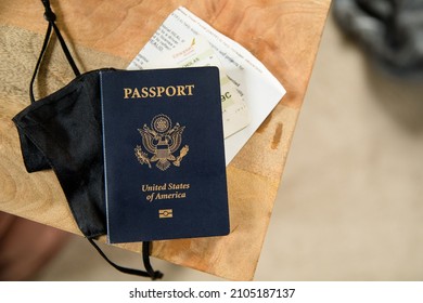 American Passport And Black Face Mask On Wood Desk Background, Covid Travel, Traveling With Covid, Pandemic Travel