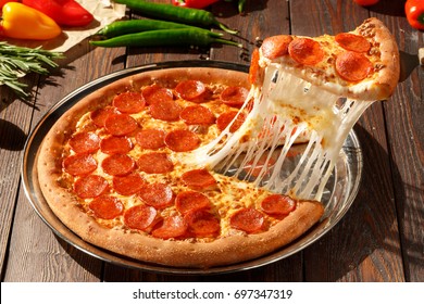 American pizza with pepperoni, mozzarella and tomato sauce. Pizza on a wooden table, morning, dawn.