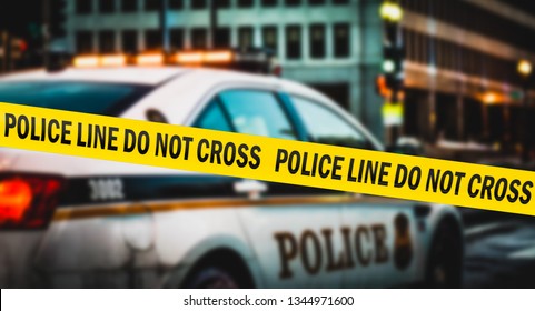 American Police Tape Hangs Near A Police Car