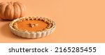 American Pumpkin Pie for autumn holiday on orange background with copy space. Close up. Happy Thanksgiving Day. Banner.