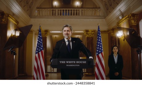 American republican politician during press conference in the White House. Confident US minister or congressman smiles, poses for cameras after political speech. USA flags in background. Slow motion. - Powered by Shutterstock