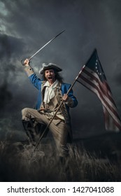 American Revolution War Soldier With Flag Of Colonies And Saber Over Dramatic Landscape. 4 July Independence Day Of USA Concept Photo Composition: Soldier And Flag.