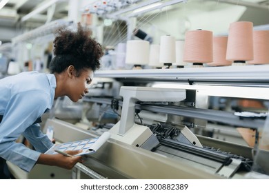 American seamstress designer with curly hair He was checking the weaving machine and the sewing thread attentively. wearing a uniform and carrying a catalog in the weaving industry - Powered by Shutterstock