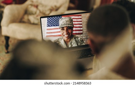 American Servicewoman Smiling Cheerfully While Video Calling Her Husband And Children From The Military Base. Happy Military Family Communicating Online.