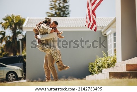American soldier embracing her husband after returning home from the army. Servicewoman having a joyful reunion with her husband after serving her country in the military.