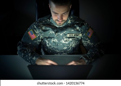 American Soldier In Military Uniform Using High Tech Computer In Headquarters Intelligence Center. Focus On US ARMY Tag And USA Flag Patch On Uniform.