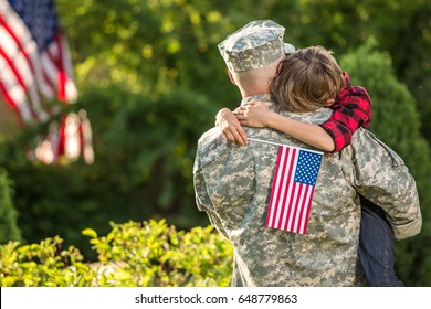 American soldier reunited with son on a sunny day with american flag on the background - Powered by Shutterstock