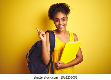 American Student Woman Wearing Backpack Holding Notebook Over Isolated Yellow Background Very Happy Pointing With Hand And Finger To The Side