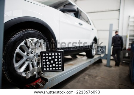 American SUV car on stand for wheels alignment camber check in workshop of service station.