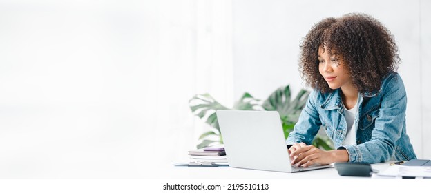 American teenage woman sitting in white office with laptop, she is a student studying online with laptop at home, university student studying online, online web education concept. - Powered by Shutterstock