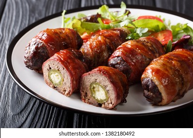 American Texas Armadillo Eggs With Jalapeno And Cheese Wrapped In Bacon Served With Fresh Salad Close-up On A Plate On The Table. Horizontal
