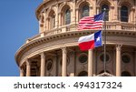 American and Texas state flags flying on the dome of the Texas State Capitol building in Austin