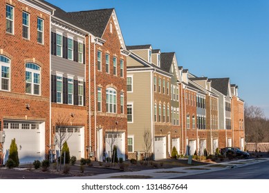 American town home neighborhood street with colorful brick and vinyl facade multi-family development project with blue sky on a sunny day in the USA somewhere in Maryland 