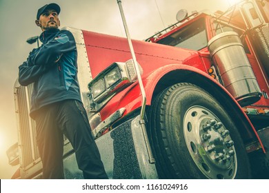 American Trucker Job. Caucasian Truck Driver In Front Of His Red Semi Truck.