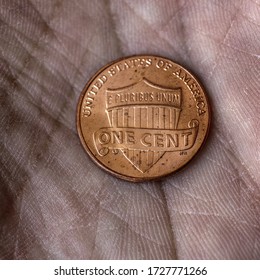 American US Coin 1 Cent Penny Lies On A Dirty Palm Close Up. An Impressive, Dramatic Square Shot With An Aged Effect. Low-wage Labor Work, Poverty, Homeless People. Macro