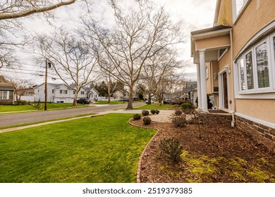 American villa community on spring day with two-story houses, asphalt road, green lawns, and leafless trees under cloudy sky. New Jersey, USA. - Powered by Shutterstock