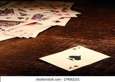 American West Legend Vintage Ace Of Spade Playing Card And Stack Of Antique Poker Game Cards On A Weathered Wood Table In An Old Western Frontier Gambling Establishment Saloon