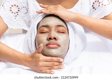 American-African Woman Uses A Mask And Has A Massage Therapist Give Her A Moisturized Facial In A Spa Salon.