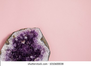 The amethyst stone on pastel pink background. Minimalism flat lay style.