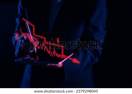 Amid a financial crisis, a focused businessman uses a tablet to analyze data, specifically a red stock graph with a significant down arrow, illustrating the alarming decrease in financial performance