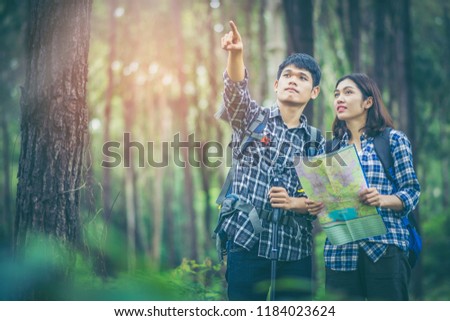 Amid the pine forests, young men and young women hikers Asians are reading a map. They are travelers, adventure lovers of nature. Studying the ecology of rainforests. The man pointing to what he sees.