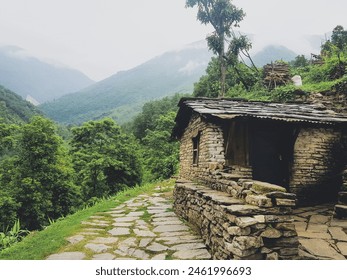 Amidst the majestic Himalayan mountain range, a solitary house finds sanctuary, its presence a humble testament to human resilience amidst nature's grandeur in the warmth of summer - Powered by Shutterstock