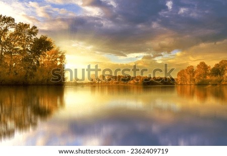 Amidst the mountains, a lone tree graces the tranquil shore, casting a perfect reflection on the still waters, a harmonious symphony of earth and water. Foto stock © 