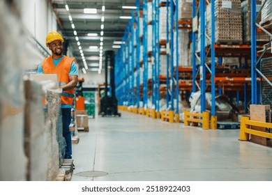 Amidst towering shelves, a focused male african american warehouse worker utilizes a laptop to manage logistics, illustrating the importance of technology in modern inventory control and management. - Powered by Shutterstock