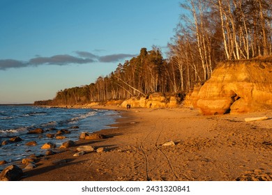Amidst the tranquil beauty of Veczemju Klintis, Latvija, the golden hour of sunset bathes the rocky beach in a warm glow, offering a moment of serenity and reflection - Powered by Shutterstock