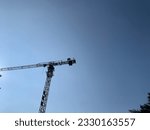 Amidst the vast expanse of a clear blue sky, a construction tower reaches towards the heavens. Its towering frame dominates the landscape, a symbol of progress and ambition.