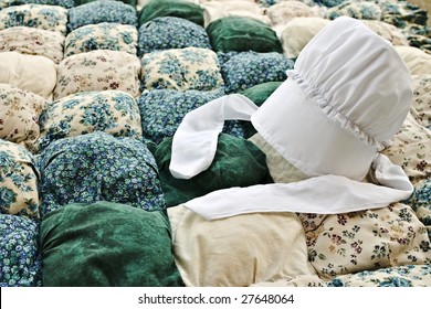 Amish Bonnet On An Old Biscuit Quilt.