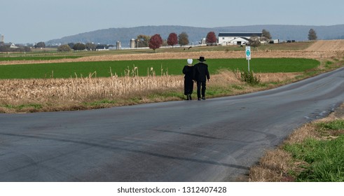 Amish Couple Walking On A Residential Road On A Summer Day