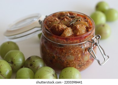 Amla Pickle Or Gooseberry Pickle Stored In A Glass Bottle. It Is A Spicy Condiment Made With Amla Also Known As Indian Gooseberries, Red Chilli Powder, Other Spices And Oil. Shot On White Background