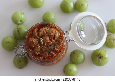 Amla Pickle Or Gooseberry Pickle Stored In A Glass Bottle. It Is A Spicy Condiment Made With Amla Also Known As Indian Gooseberries, Red Chilli Powder, Other Spices And Oil. Shot On White Background