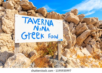 AMMOPI VILLAGE, KARPATHOS ISLAND - SEP 26, 2018: White Sign Of Greek Taverna In Front Of Rocks On Coastal Path In Ammopi Village. Greek Islands Are Famous For Great Food And Healthy Lifestyle.