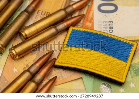 Ammunition and Ukraine flag patch placed on euro banknotes as defense spending concept