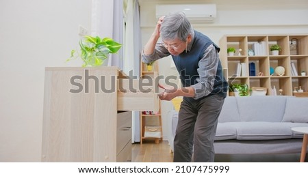 Amnesia and memory loss - asian older man wearing reading glasses is through all the drawers and he forgot something