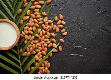 Amond seeds with bowl of fresh natural milk placed on black stone background