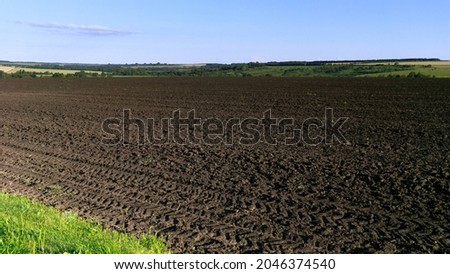 Among the green fields is a plot of land plowed for sowing grain crops. The blue sky is visible on the horizon.
