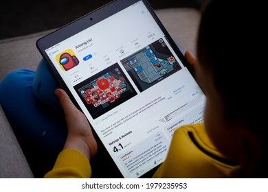 Among US game app seen on the screen of ipad which is in the hands of  unrecognisable child. Concept. Stafford, United Kingdom, May 18, 2021.