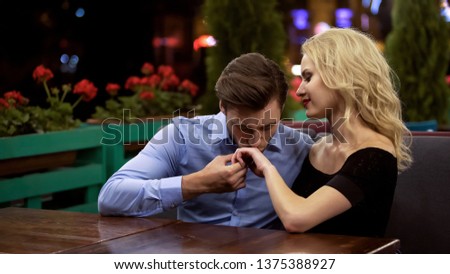 Amorous admirer kissing hand of his beautiful lady, sitting in cozy restaurant